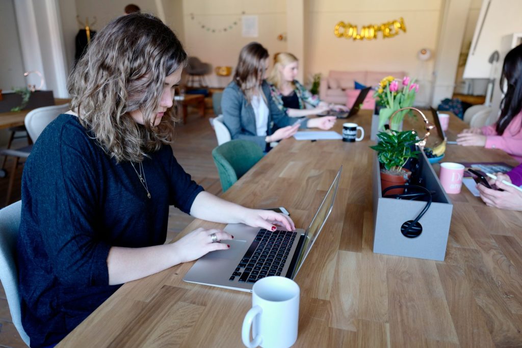 Mujeres en una sala usando Macbooks